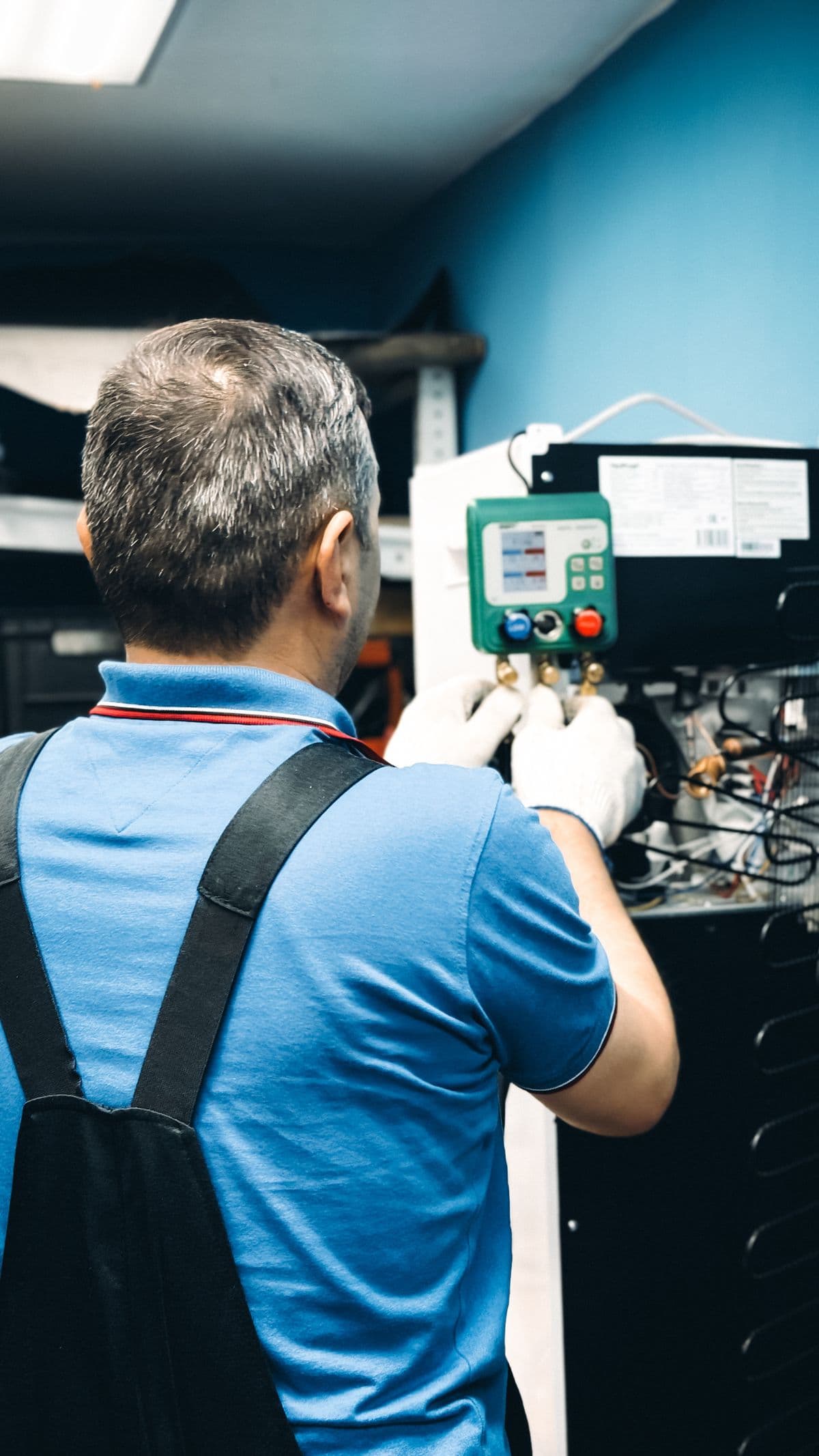 Técnico con guantes midiendo con manómetros de refrigerante en una unidad de aire acondicionado — Instalación de mini splits en Bucaramanga y Barranquilla