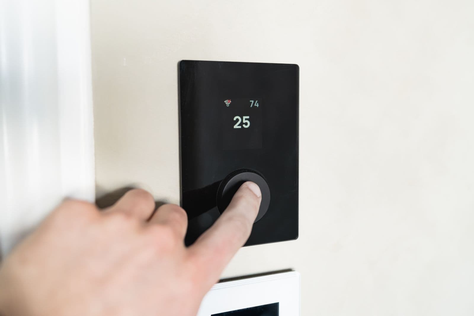 Mano ajustando un termostato inteligente de pared — Termostatos y controles en Bucaramanga y Barranquilla