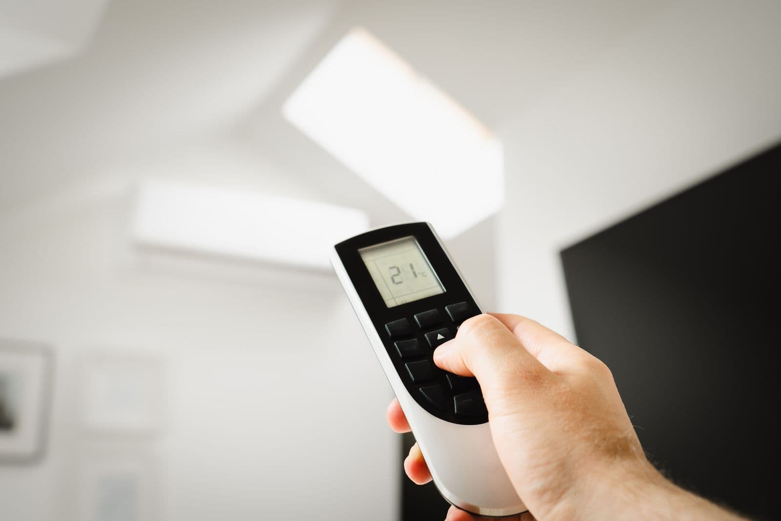 Mano ajustando la temperatura con el control remoto de un aire acondicionado split de pared — Instalación de mini splits en Bucaramanga y Barranquilla