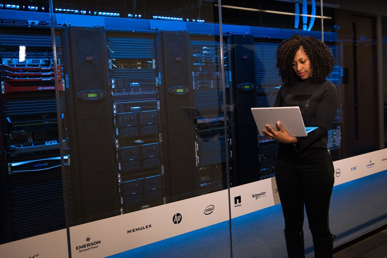 Racks de servidores en un data center con una ingeniera revisando equipos con laptop — HVAC para data centers en Bucaramanga y Barranquilla