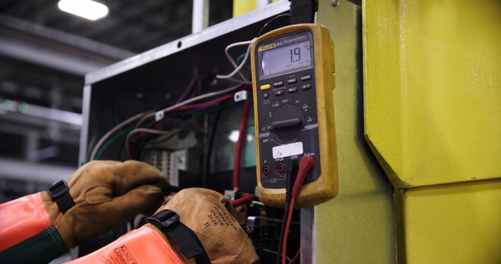Electricista midiendo con multímetro dentro de un tablero eléctrico industrial abierto — Mantenimiento correctivo en Bucaramanga y Barranquilla